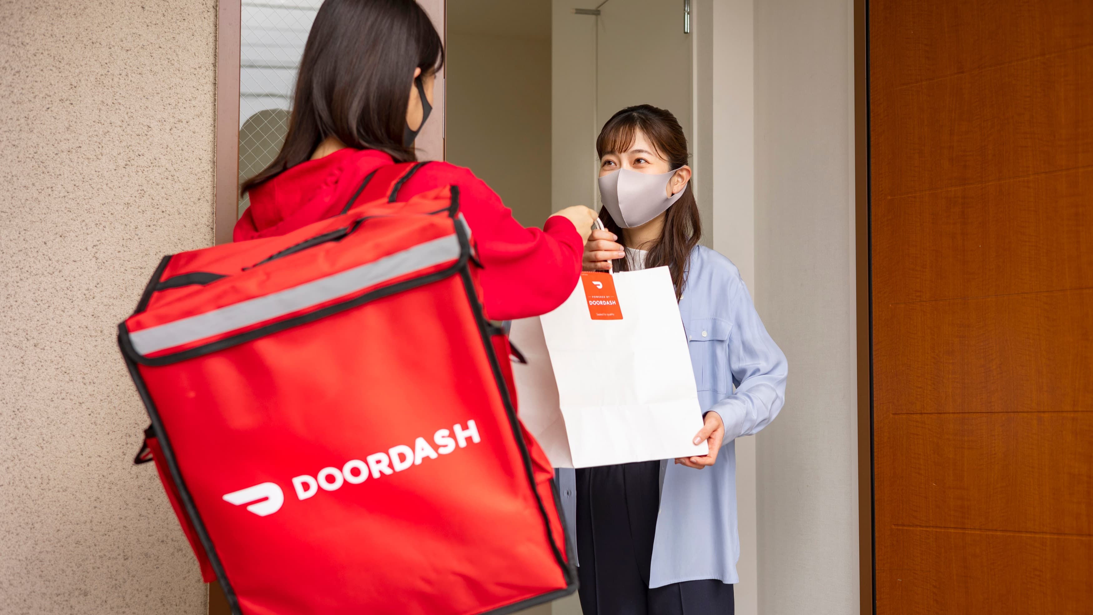 A DoorDash courier handing over a restaurant order